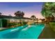 Long rectangular pool illuminated at twilight, surrounded by manicured shrubs and the home's exterior at 2110 Reaney Rd, Lakeland, FL 33803