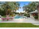 A beautiful backyard featuring a pristine in-ground swimming pool, surrounded by lush greenery and an outdoor seating area at 2110 Reaney Rd, Lakeland, FL 33803
