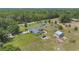 Aerial view featuring a green home with a patio and outbuildings surrounded by vibrant trees at 21551 Lake Seneca Rd, Eustis, FL 32736