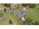 Aerial view featuring a home with fenced garden, greenhouse, outbuildings, and a driveway, surrounded by a lush landscape at 21551 Lake Seneca Rd, Eustis, FL 32736
