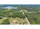 Aerial view showing a property with a home, lush trees, and a road leading to a tranquil lake at 21551 Lake Seneca Rd, Eustis, FL 32736