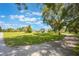 Exterior home view highlighting the driveway, yard, and surrounding trees under a blue sky at 21551 Lake Seneca Rd, Eustis, FL 32736
