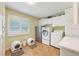 A spacious laundry room featuring modern washer and dryer, a utility sink, and plenty of storage at 21551 Lake Seneca Rd, Eustis, FL 32736