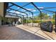 The enclosed patio has stone floors, a grill, table and chairs and a view of a well maintained yard at 21551 Lake Seneca Rd, Eustis, FL 32736