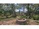 Backyard view featuring a brick fire pit under the shade of mature trees at 1625 Itchepackesassa Dr, Lakeland, FL 33810