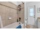 Bathroom with ceramic tiled walls, tub with shower, and commode and door adjacent at 2921 Se 38 Pl, Ocala, FL 34480