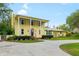 Charming yellow two-story home with a covered front porch, lush landscaping, and a welcoming driveway at 1226 Se 9Th Ave, Ocala, FL 34471