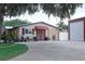 Charming home exterior featuring a red-awning entrance, mature landscaping, and long driveway at 1423 Spruce N Rd, Lakeland, FL 33809