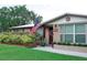 Home featuring brick accents, updated windows, mature landscaping, and an American flag at 1423 Spruce N Rd, Lakeland, FL 33809