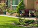 Charming front porch features a cozy seating area surrounded by colorful flower beds and yard decor at 1423 Spruce N Rd, Lakeland, FL 33809