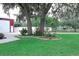 Beautifully landscaped yard with mature trees, colorful flowers, and vibrant green grass at 1423 Spruce N Rd, Lakeland, FL 33809