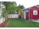Backyard view of the shed with AC, surrounded by lush greenery and a white fence at 1423 Spruce N Rd, Lakeland, FL 33809