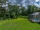 View of the backyard with the screened-in pool, green lawn and lush foliage at 3952 Laurel Branch Dr, Lakeland, FL 33810