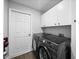 Modern laundry room with dark gray washer and dryer, white cabinets, and door to exterior at 3952 Laurel Branch Dr, Lakeland, FL 33810