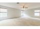 Expansive carpeted bedroom features three large windows and a ceiling fan, offering lots of natural light at 1769 Strathmore Cir, Mount Dora, FL 32757