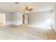 An airy living room features neutral carpet and large windows and a ceiling fan for a bright and comfortable space at 1769 Strathmore Cir, Mount Dora, FL 32757
