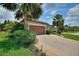 Charming paver driveway, lush greenery, and mature palm trees leading to the home's entrance and two-car garage at 224 Granada Ln, Davenport, FL 33837