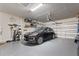 Well-lit two-car garage with shelving and a black car, offering practical storage solutions at 224 Granada Ln, Davenport, FL 33837