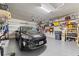 Clean and organized two-car garage featuring ample storage shelves, overhead lighting, and black car inside at 224 Granada Ln, Davenport, FL 33837
