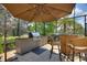Outdoor kitchen with stainless steel grill and bar seating in screened patio at 224 Granada Ln, Davenport, FL 33837