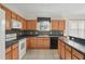 Well-lit kitchen features wood cabinets, black countertops, tile backsplash, and modern appliances at 442 Graystone Blvd, Davenport, FL 33837