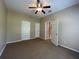 Bedroom with neutral walls, carpet, ceiling fan, and multiple doors, offering versatility and privacy at 10303 Park Commons Dr, Orlando, FL 32832