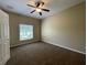 Neutral bedroom features tan walls, brown carpet, ceiling fan, and natural light from the window at 10303 Park Commons Dr, Orlando, FL 32832