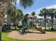 Community playground with slides, a small climbing structure, and palm trees with neighborhood in the background at 10303 Park Commons Dr, Orlando, FL 32832