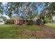 A spacious backyard with mature trees and green grass surround the house with a screened-in patio at 10421 Mesa Ln, Clermont, FL 34711