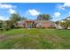 Charming brick home with a well-manicured lawn and inviting front entrance, surrounded by mature trees at 10421 Mesa Ln, Clermont, FL 34711