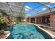 Inviting screened-in pool area with waterfall feature, surrounding landscaping and connected patio at 10421 Mesa Ln, Clermont, FL 34711