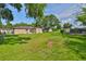 View of spacious backyard, partially fenced, with sunny lawn and mature trees, plus solar panels on rear of the home at 1110 Waterview E Blvd, Lakeland, FL 33801