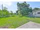 View of spacious, fenced backyard with sunny lawn and mature trees, plus partial view of house siding at 1110 Waterview E Blvd, Lakeland, FL 33801