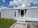 Home exterior featuring gray siding, a well-kept lawn, and a welcoming front entrance with storm door at 1206 Skyview Cv, Lakeland, FL 33801