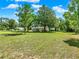 Expansive front yard of the home with mature trees and blue skies creating an inviting atmosphere at 28712 Azalea Ave, Paisley, FL 32767