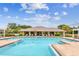 Stunning community pool with an open-air clubhouse featuring chairs for lounging and brick trim around the pool at 7991 Lake James Blvd, Lakeland, FL 33810