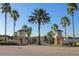 View of the gated entrance to the community with palm trees and meticulously maintained landscaping at 189 Minniehaha Cir, Haines City, FL 33844