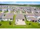 An aerial view of a suburban neighborhood showcases homes with verdant lawns, driveways and manicured landscapes under bright sunlight at 2296 Crossbow St, Clermont, FL 34715