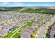 From above, a neighborhood shows off its homes with manicured lawns, white fences, and a shared community pool at 2296 Crossbow St, Clermont, FL 34715