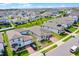 An aerial view captures a vibrant residential street with neatly lined homes, brick driveways, and manicured lawns under a bright sky at 2296 Crossbow St, Clermont, FL 34715