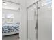 Bright bathroom featuring a glass-enclosed shower, and a bedroom in the background at 2296 Crossbow St, Clermont, FL 34715
