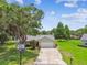 Classic home featuring a well-manicured lawn, mature trees, and a basketball hoop in the driveway at 4221 Meadowbend Ct, Lakeland, FL 33811
