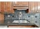 Close up of the kitchen sink with dark countertops and patterned backsplash at 4221 Meadowbend Ct, Lakeland, FL 33811