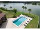 Aerial view of pool on lakeside property featuring palm trees and lounge chairs at 1920 E Edgewood Dr # E1, Lakeland, FL 33803