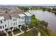 Picturesque aerial view of modern townhomes with lakefront, lush landscaping, and sidewalk at 12684 Willstatter Ave, Orlando, FL 32827