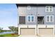 Modern two-story townhome with a gray exterior, private garage, and a glimpse of a serene lake view at 12684 Willstatter Ave, Orlando, FL 32827