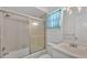 Cozy bathroom features a shower-tub combo with glass doors and a bright vanity area with a window at 3582 Milano Ave, Lakeland, FL 33803