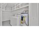 Laundry room with white washer and dryer, shelves for storage, and water heater at 3582 Milano Ave, Lakeland, FL 33803