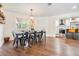 Open-concept dining area flows into a modern kitchen, featuring sleek black dining set and wood flooring at 3120 S Polk Ave, Lakeland, FL 33803