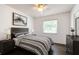 This bedroom features a modern design with a stylish striped bedspread, dark wood floors, and ample natural light from the window at 4102 Stonehenge Rd, Mulberry, FL 33860